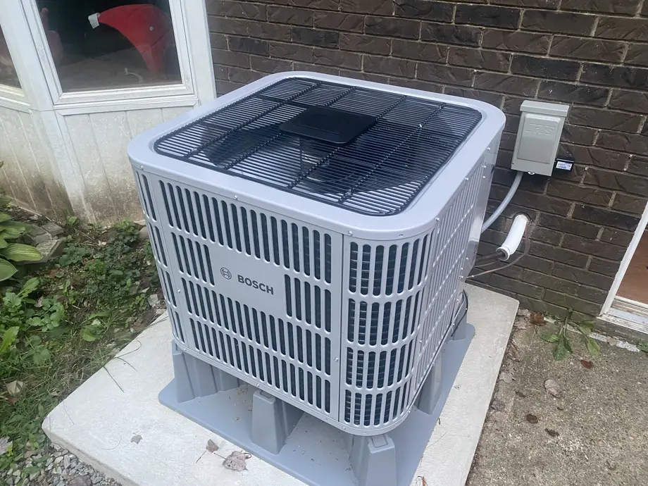 Bosch outdoor heat pump on concrete pad beside a brick home