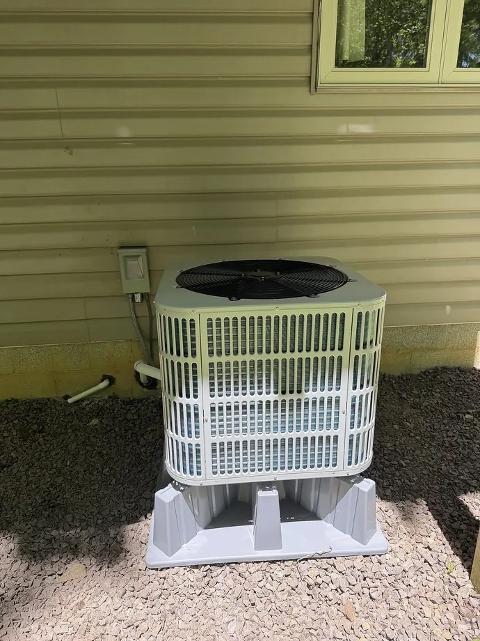 Installed white outdoor Bosch condenser beside green siding