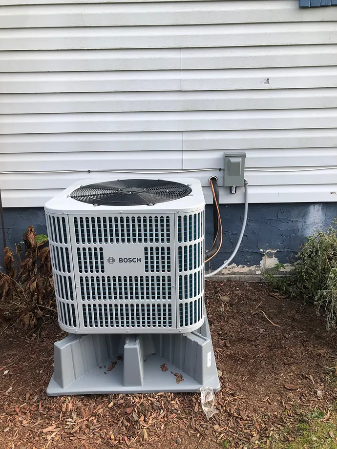 White outdoor Bosch condenser installed next to light house siding