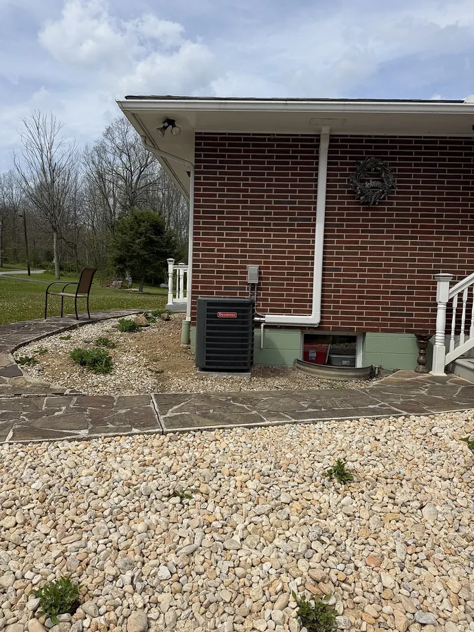 Brick residence with installed outdoor condenser and finished white line cover