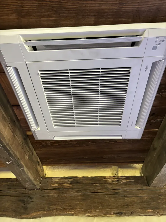 White Fujitsu cassette unit installed in wood ceiling